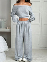 Woman wearing light gray off-shoulder crop top and wide-leg lounge pants set, relaxed fit