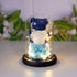 Glass dome with blue teddy bear, white rose, blue flowers, and soft LED lights on black base.
