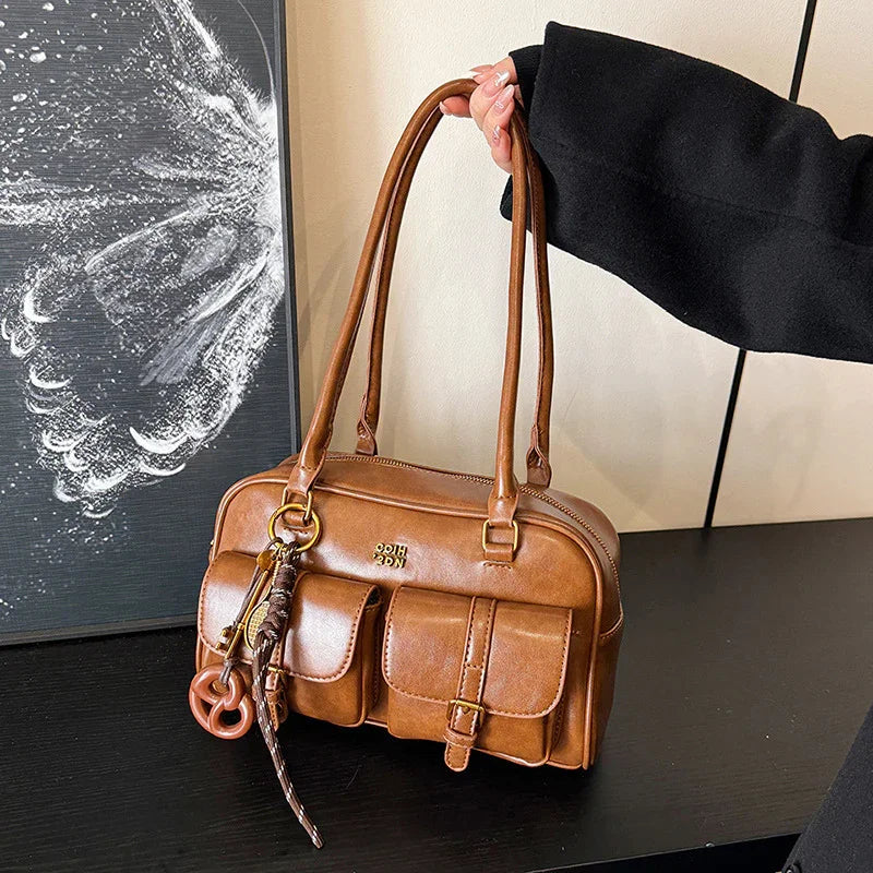 Brown faux leather shoulder bag with front pockets, structured shape, and long handles