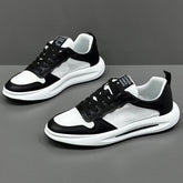 Black and white low-top mesh sneakers with leather accents and chunky sole on gray background