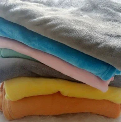 Stack of soft fleece blankets in gray, blue, pink, yellow, and orange, folded neatly