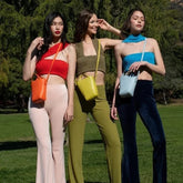 Three women wearing colorful ribbed knit crop tops and high-waisted pants, posing outdoors