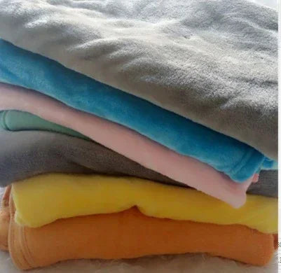 Stack of folded fleece blankets in gray, blue, pink, yellow, and orange, soft fabric.