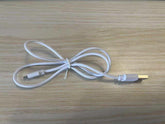 White USB charging cable with micro USB connector, flexible plastic material, on wood surface