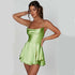 Woman wearing a lime green satin mini dress with spaghetti straps and layered skirt