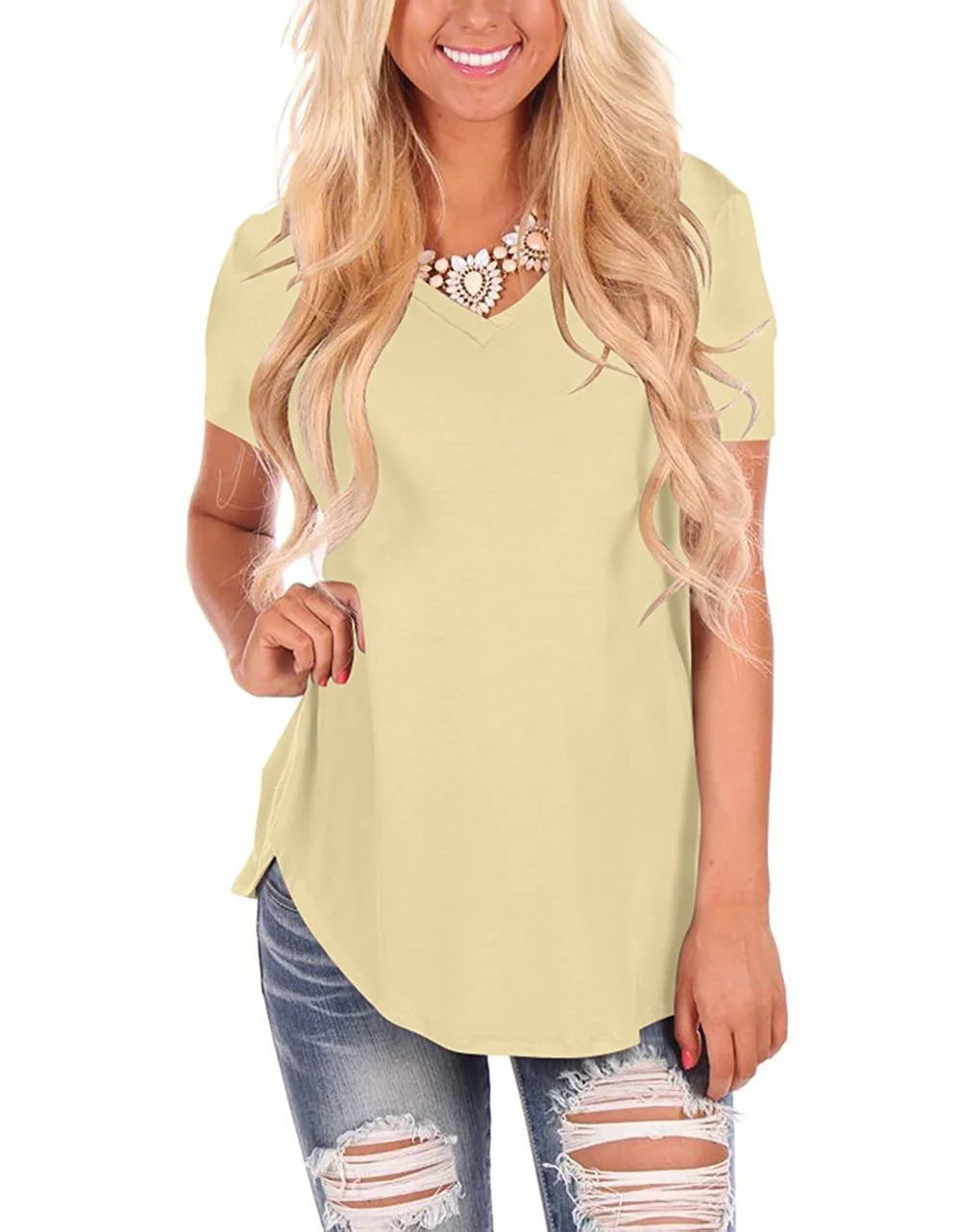 Woman in light yellow short sleeve V-neck top, relaxed fit, paired with ripped jeans