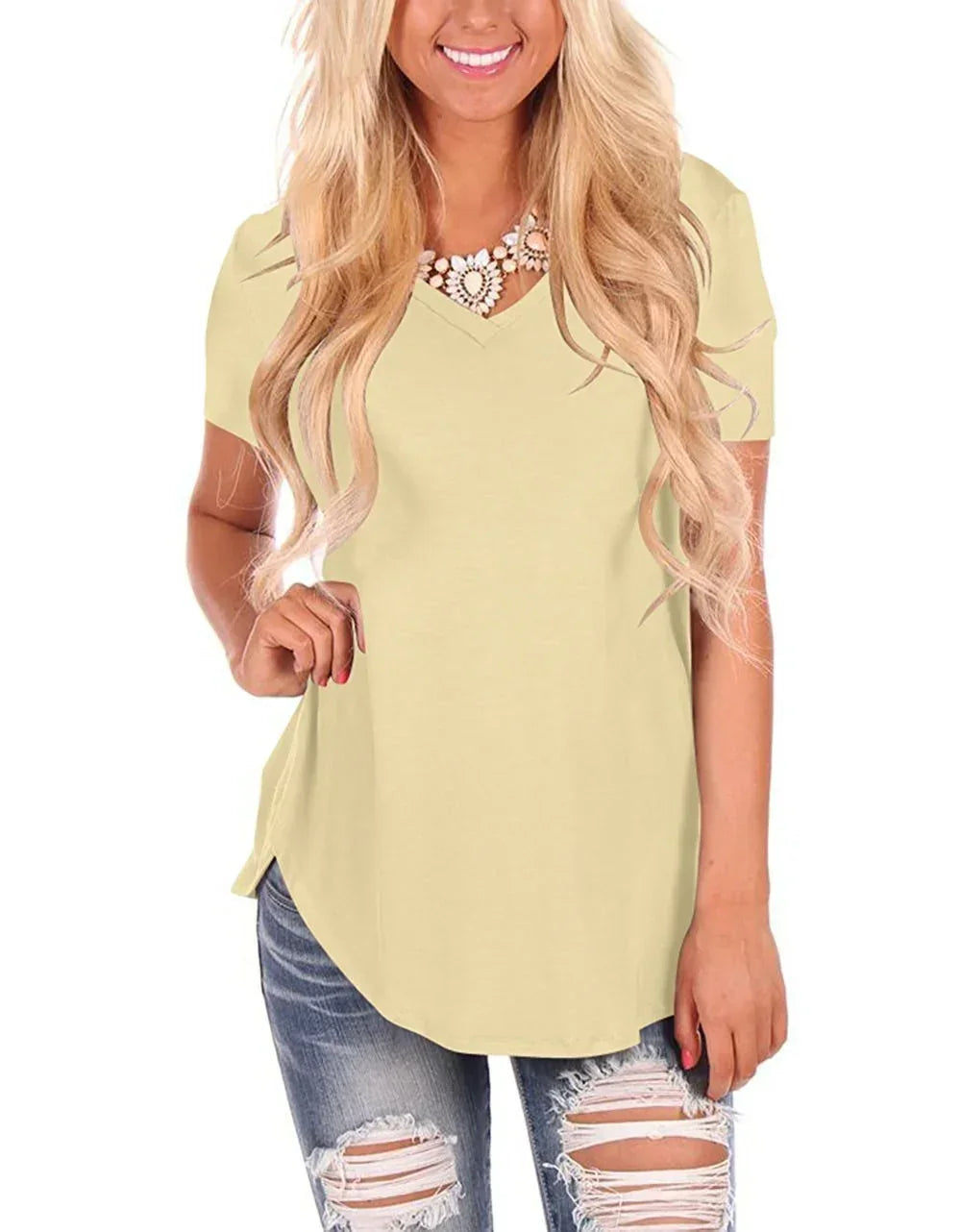 Woman in light yellow short sleeve V-neck top, relaxed fit, paired with ripped jeans
