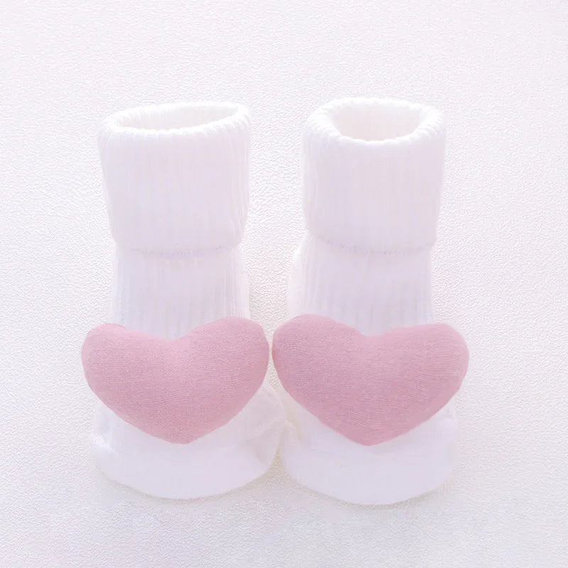 White ribbed baby socks with soft pink heart accents on toes, cozy cotton material, cute design.