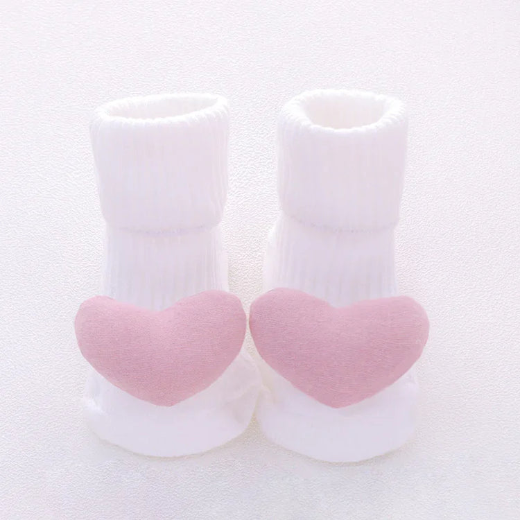 White ribbed baby socks with soft pink heart accents on toes, cozy cotton material, cute design.