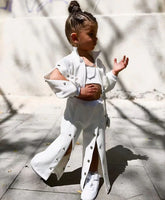 Child wearing white streetwear set with snap buttons, wide-leg pants, crop top, and sneakers