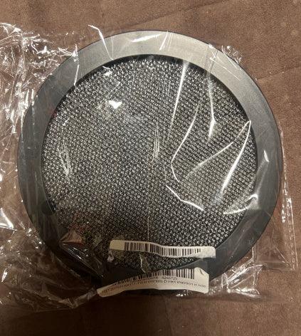 Round metallic mesh filter with black edge, packaged in clear plastic, on brown fabric
