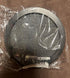 Round metallic mesh filter with black edge, packaged in clear plastic, on brown fabric