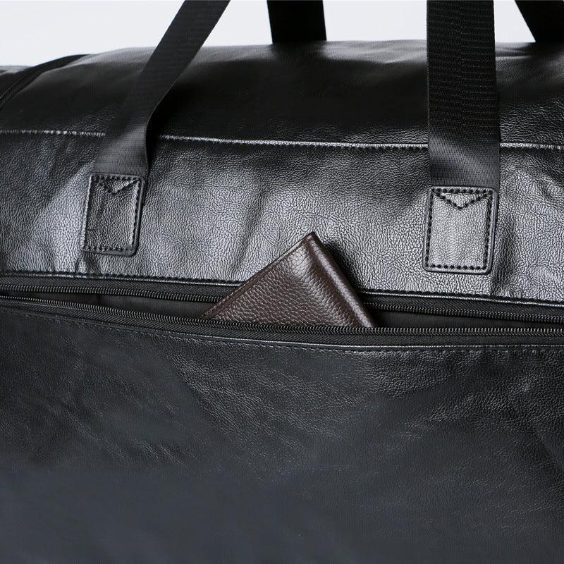 Black leather duffel bag with zip pocket, textured material, and a brown wallet visible