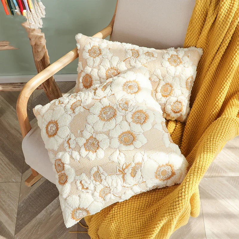 Cream floral textured throw pillows on beige chair with yellow knit blanket, cozy home decor