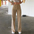 Woman wearing high-waisted beige wide-leg pants and a white crop top in a parking garage