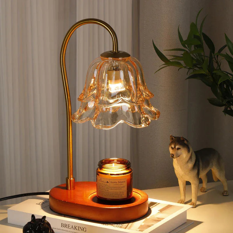 Glass flower-shaped table lamp with gold stem and wooden base on a nightstand