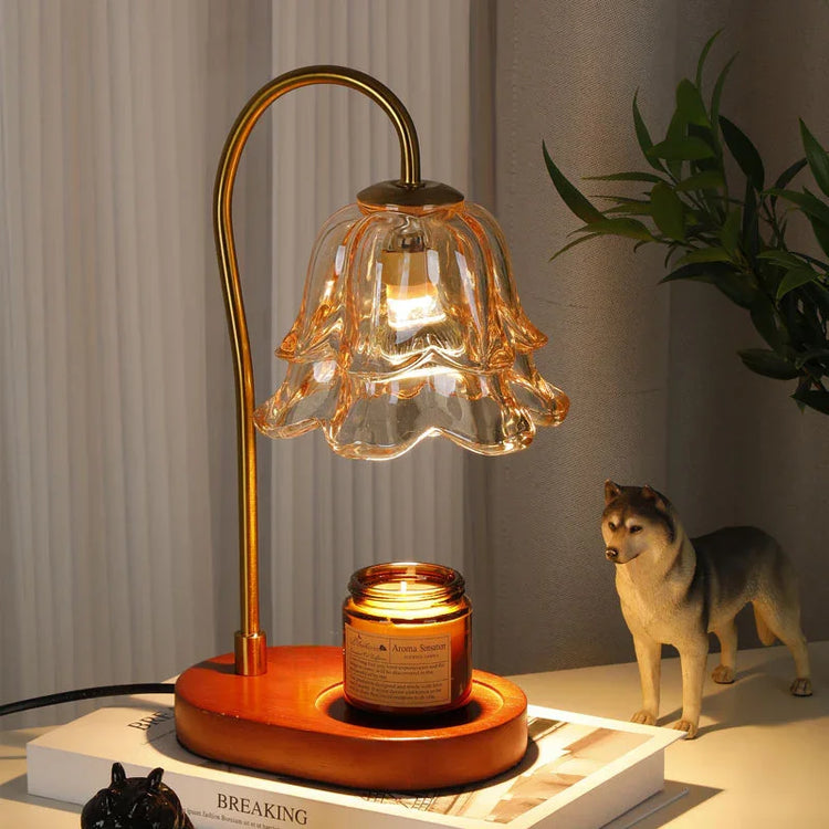 Glass flower-shaped table lamp with gold stem and wooden base on a nightstand