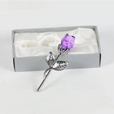 Silver metal rose with purple crystal flower in gift box on white satin