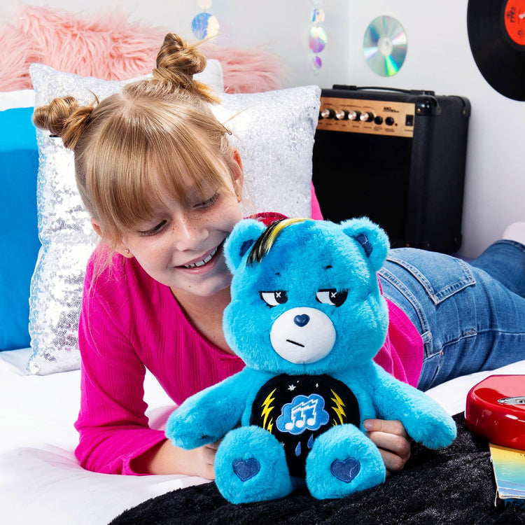 Child playing with 14-inch blue Rock-a-Lot Grumpy Bear plush featuring musical belly badge and lightning paw prints