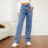 Woman wearing high-waisted blue wide-leg jeans, white crop top, casual streetwear style
