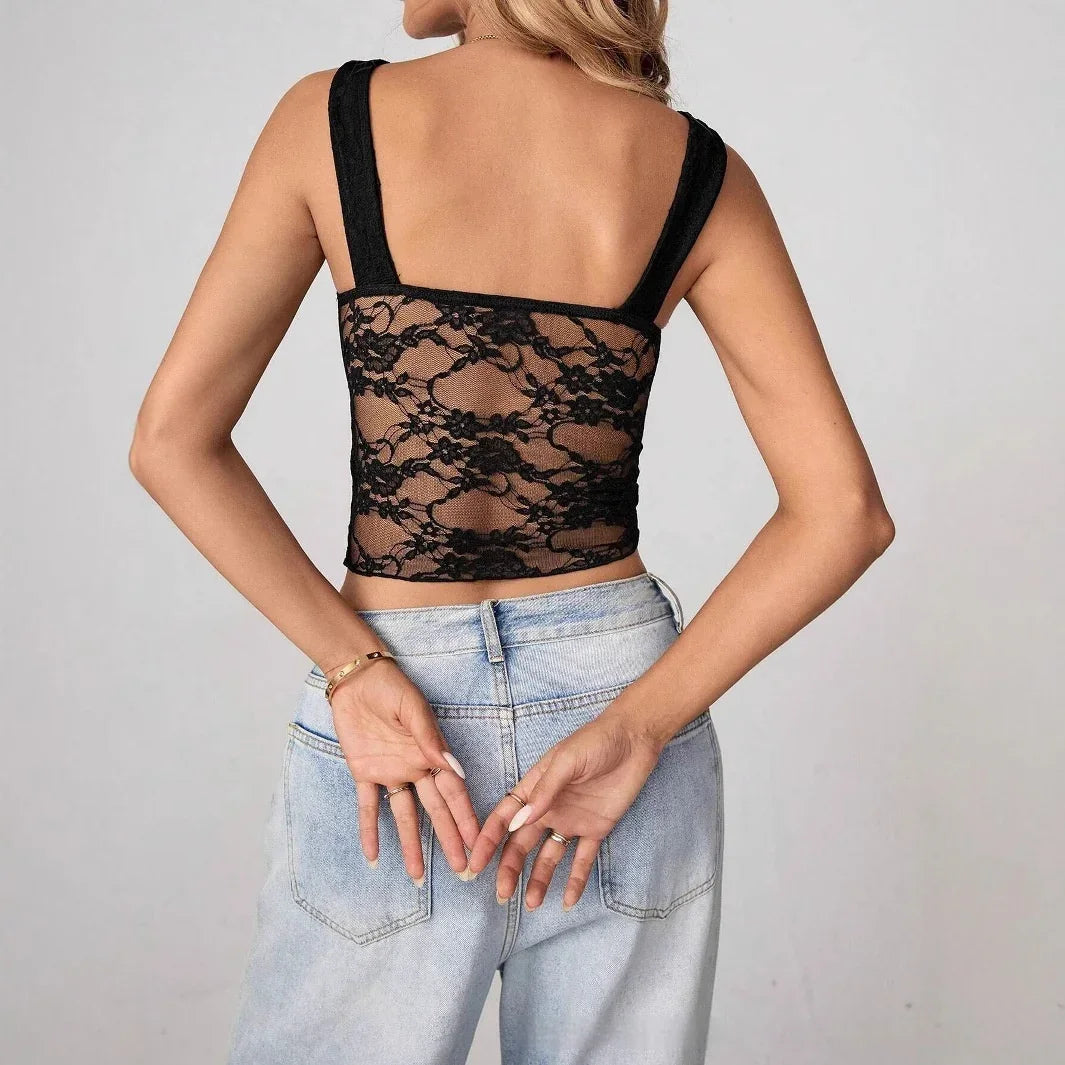 Woman in a black sheer lace crop top with wide straps and light-wash high-waisted jeans