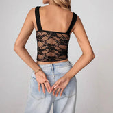 Woman in a black sheer lace crop top with wide straps and light-wash high-waisted jeans