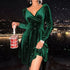 Woman wearing an emerald green velvet long sleeve mini dress with a fitted waist