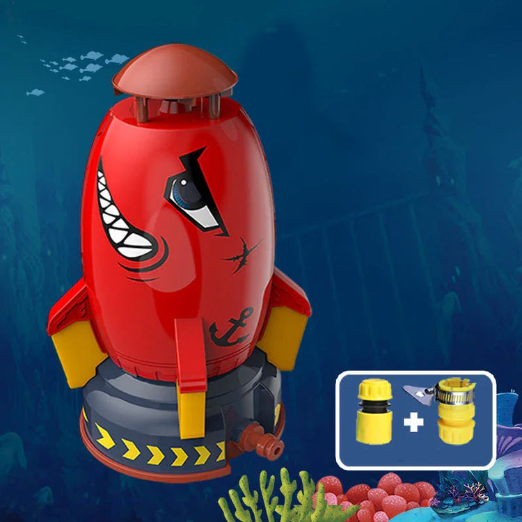 Red and yellow cartoon rocket-shaped sprinkler toy with shark face illustration, suitable for outdoor water play.