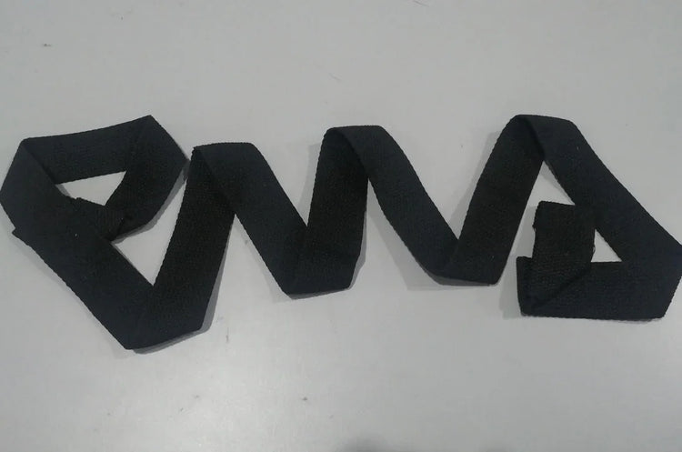 Black textured fabric belt arranged in geometric zigzag shape on a light surface