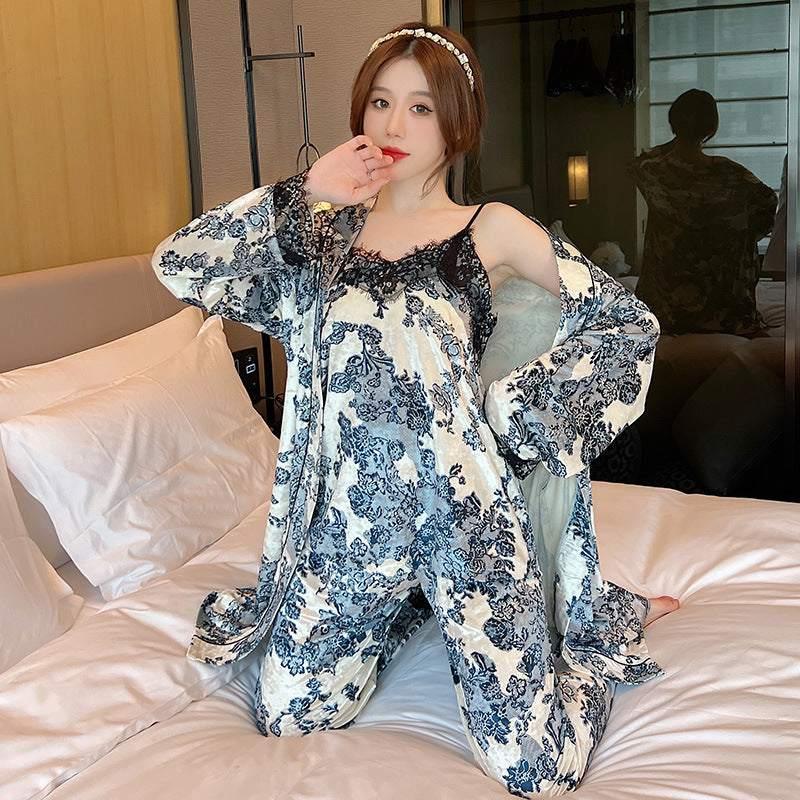 Woman wearing loose fit cream and navy floral pajamas with lace trim, sitting on bed