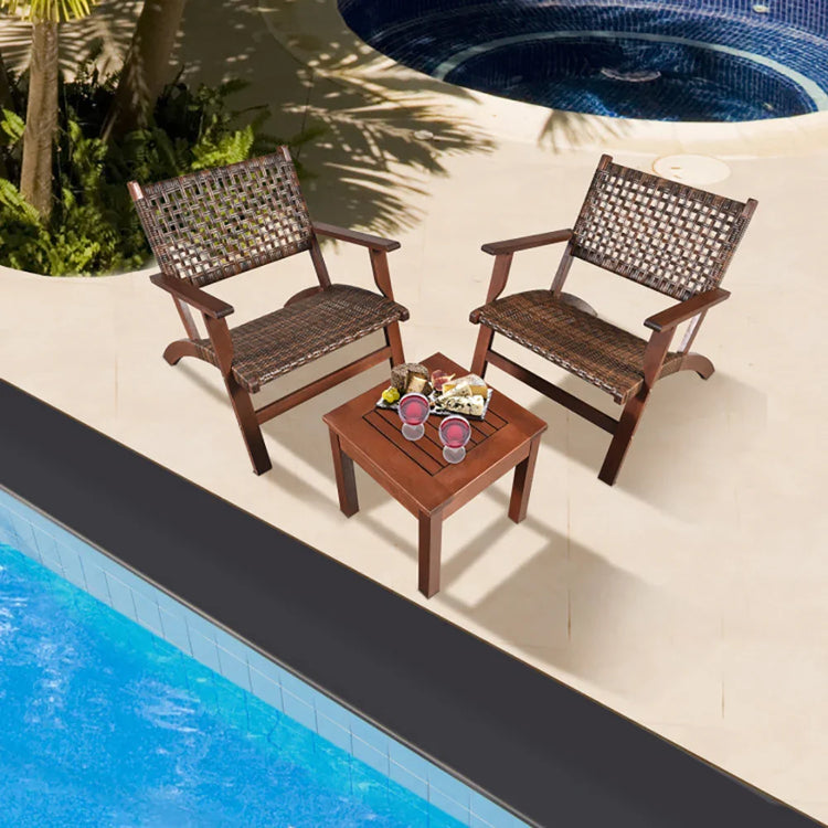 Two brown woven outdoor lounge chairs and wooden table by a pool with drinks and snacks