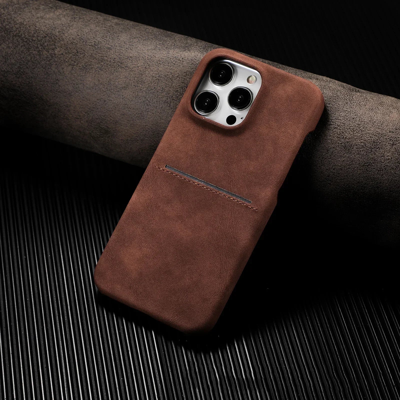Brown leather phone case with slim fit and stitched card slot on black textured surface