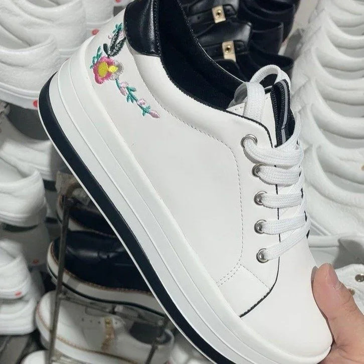 White leather sneaker with black heel, floral embroidery, and platform sole, lace-up style