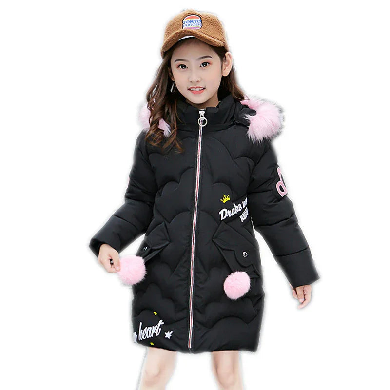 Girl wearing a black puffer coat with pink faux fur trim, long sleeves, and embroidered details