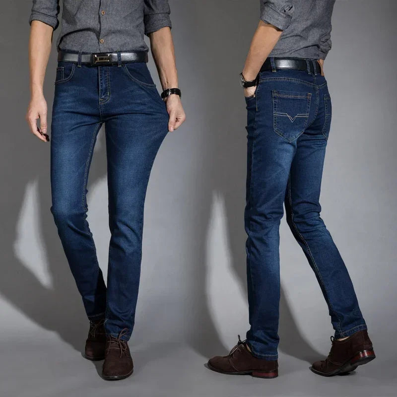 Men's slim fit dark blue denim jeans, mid-rise, casual style with pockets, paired with brown shoes.