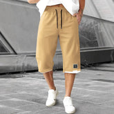 Beige knee-length streetwear shorts with black drawstring, relaxed fit, and white sneakers