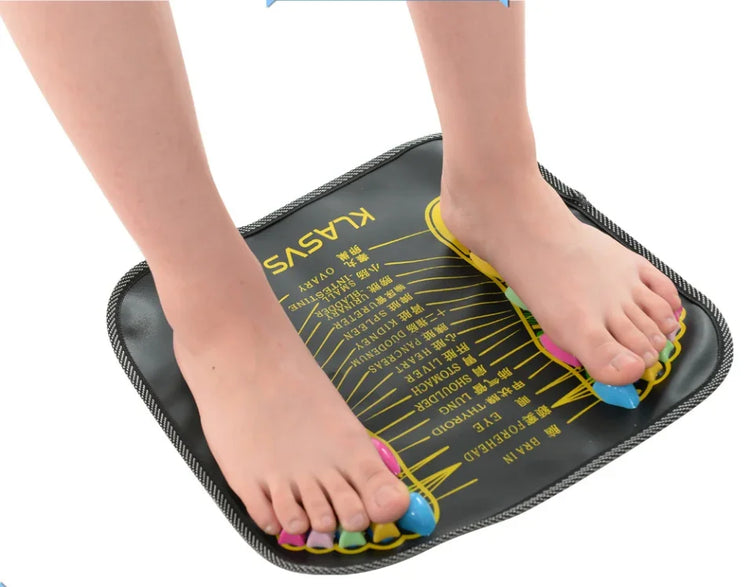 Bare feet on a black acupressure massage mat with colorful toe separators