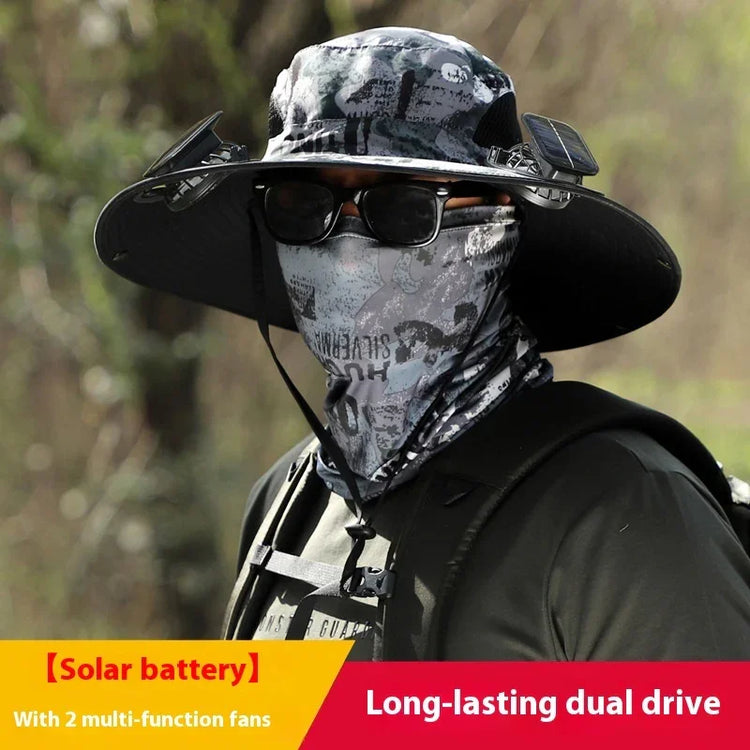 Man wearing black solar-powered fan hat, graphic bandana face mask, and dark outdoor clothing