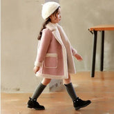 Girl wearing a pink wool coat with faux fur trim, gray knee-high socks, and black boots