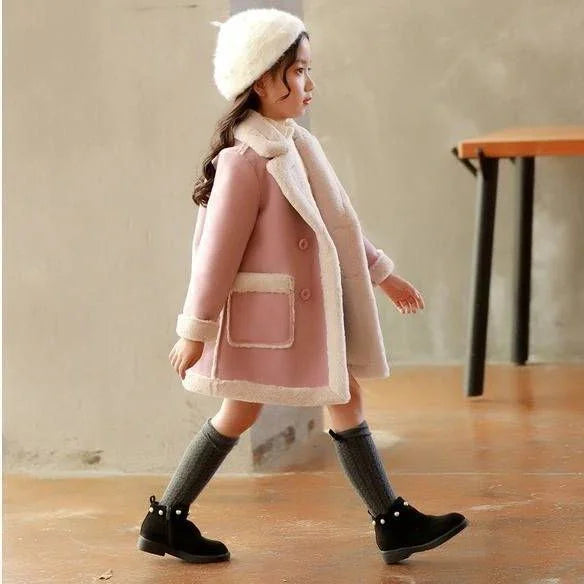 Girl wearing a pink wool coat with faux fur trim, gray knee-high socks, and black boots