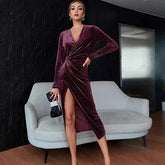 Woman wearing a deep burgundy velvet wrap dress with long sleeves and a thigh-high slit.
