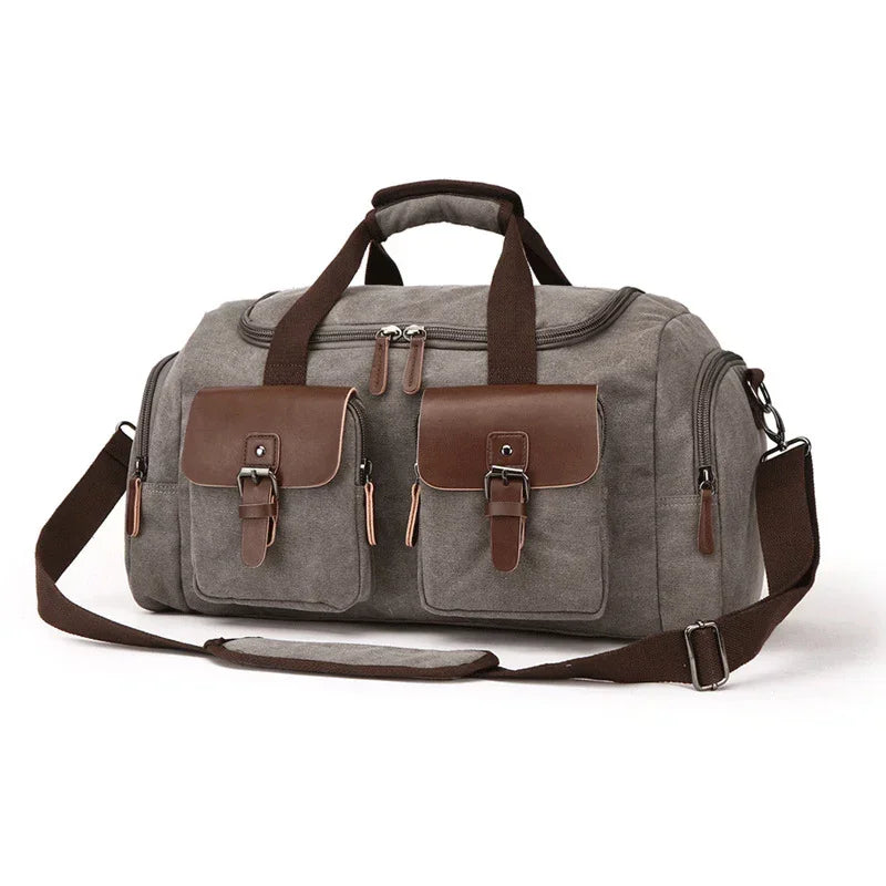 Gray canvas duffel bag with brown leather accents, buckle pockets, and adjustable strap