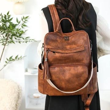 Woman wearing brown faux leather backpack with tassel, casual streetwear style