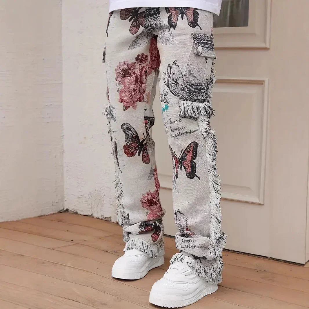 Beige straight-leg jeans with fringe trim, butterfly and floral print, relaxed streetwear fit.