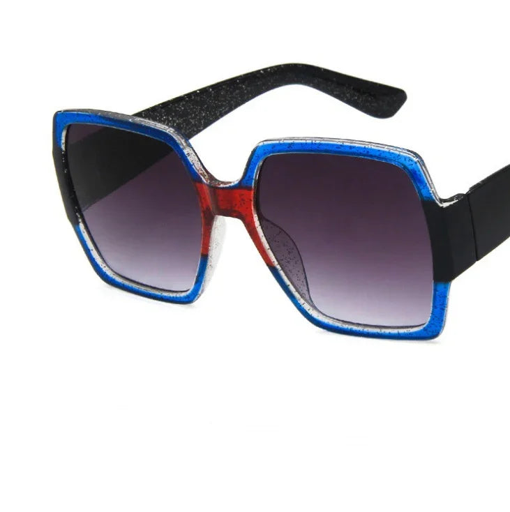 Square oversized sunglasses with blue and red acetate frame, black arms, and gradient lenses.