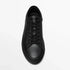 Minimalist black leather sneaker with lace-up design and low-top fit on white background