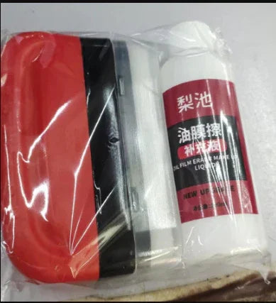 Red and black plastic scraper tool with a white bottle of cleaning liquid in clear packaging