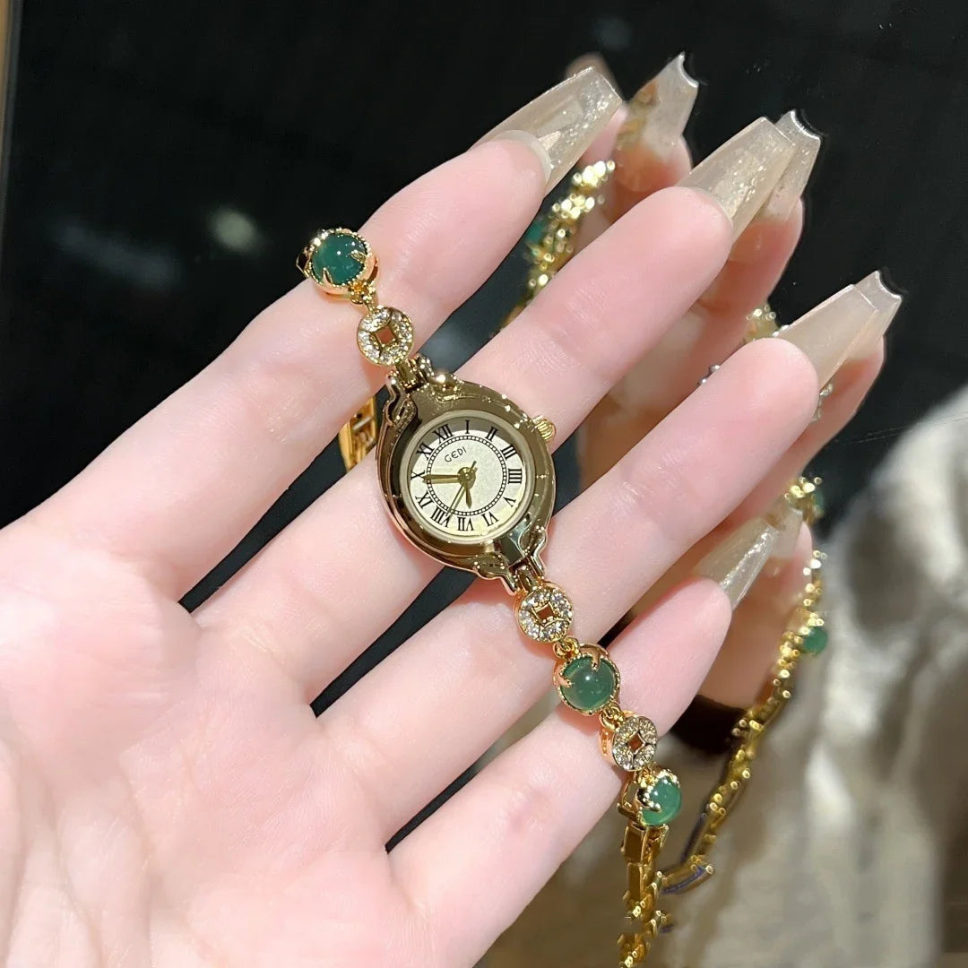 Gold bracelet watch with green gemstone accents, elegant roman numeral dial, slim fit