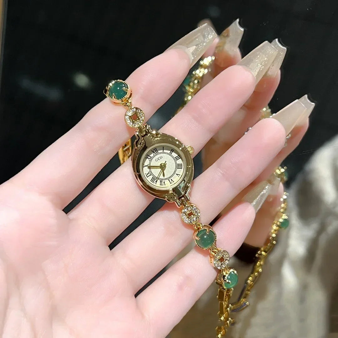 Gold bracelet watch with green gemstone accents, elegant roman numeral dial, slim fit