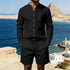 Man in black button-up linen shirt and shorts set, relaxed fit, standing by blue sea.